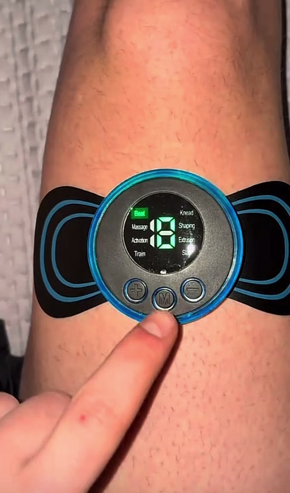 Masajeador muscular portátil con electroestimulación en uso ajustando intensidad para aliviar dolor y mejorar la recuperación